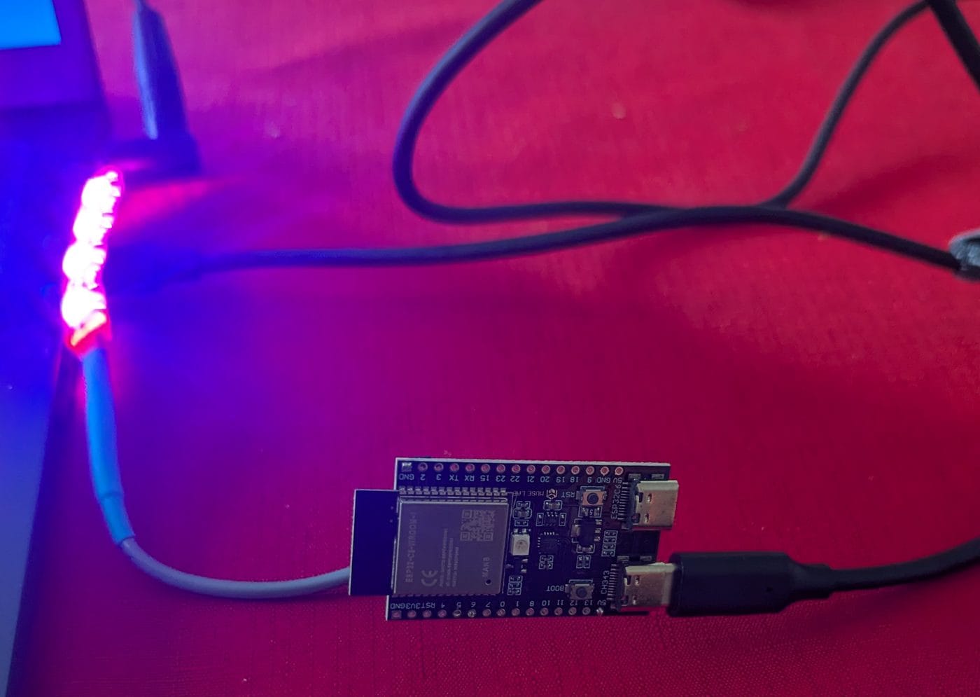ESP32-C6 board with its WS2812B strip glowing magenta in captive portal mode
